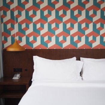 red and blue wallpaper alongside a white bed